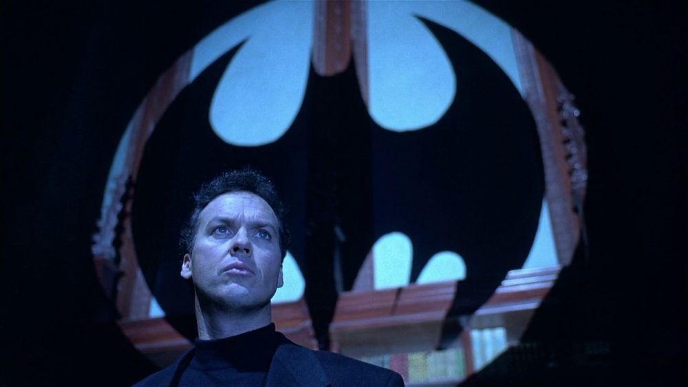 Bruce Wayne (Michael Keaton) faces a silhouette of the bat signal in Batman Returns.